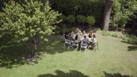 Young-friends-gathering-around-table-in-backyard